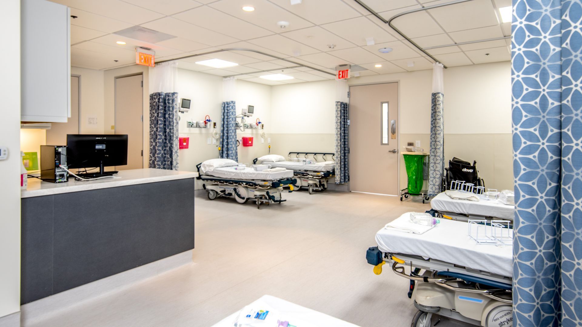 Emergency room with three beds, medical equipment, and curtains.