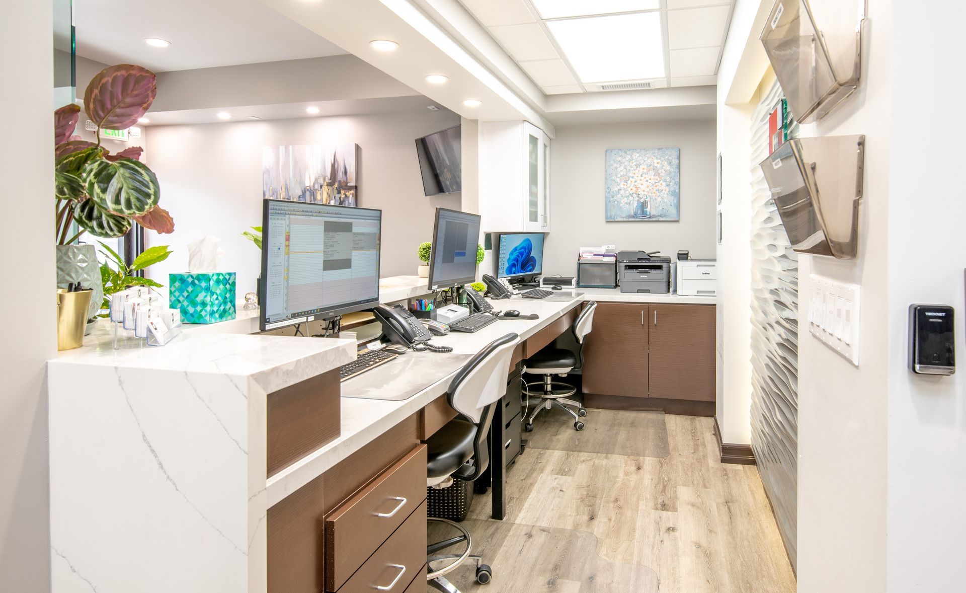 Reception area of an office with a marble countertop, computers, and a printer.