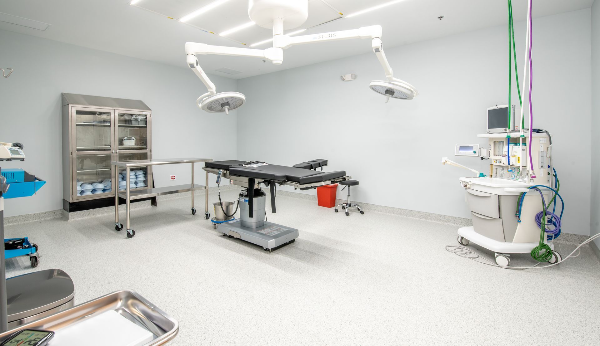 Surgical suite with operating table, medical equipment, and bright overhead lights.