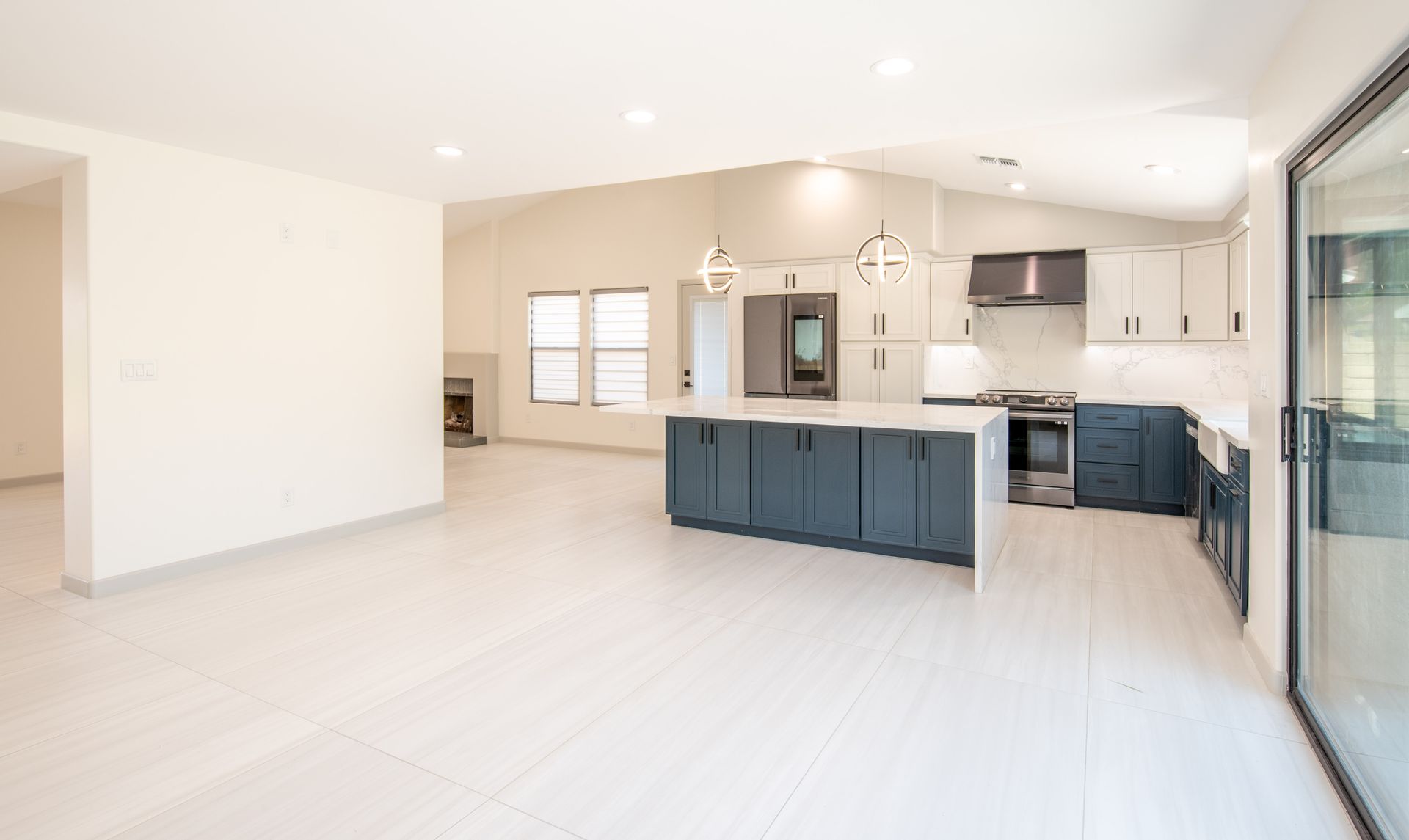 Open-concept kitchen with blue island, white cabinets, and stainless steel appliances.