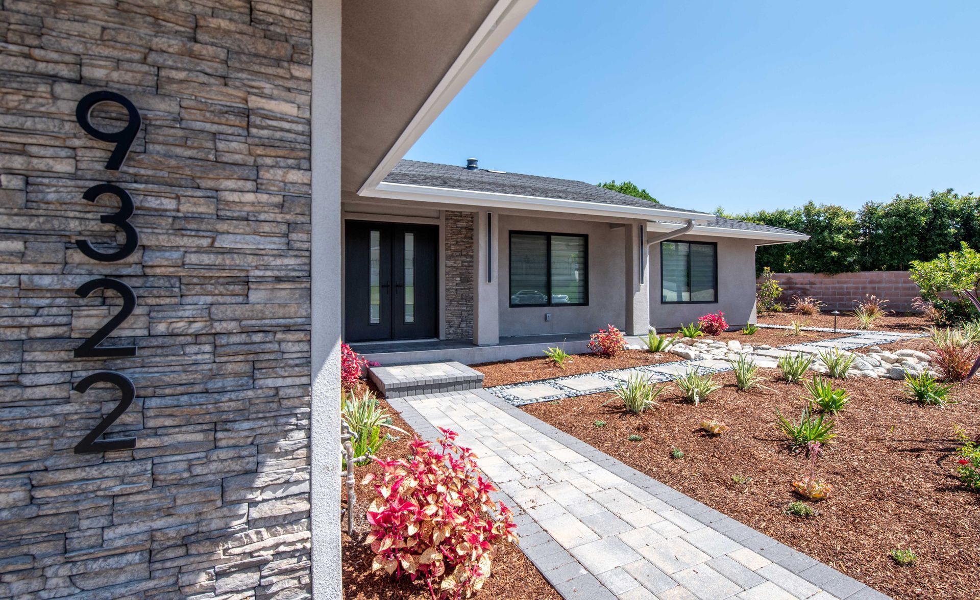 House exterior with stone facade address numbers, pathway, and landscaping.