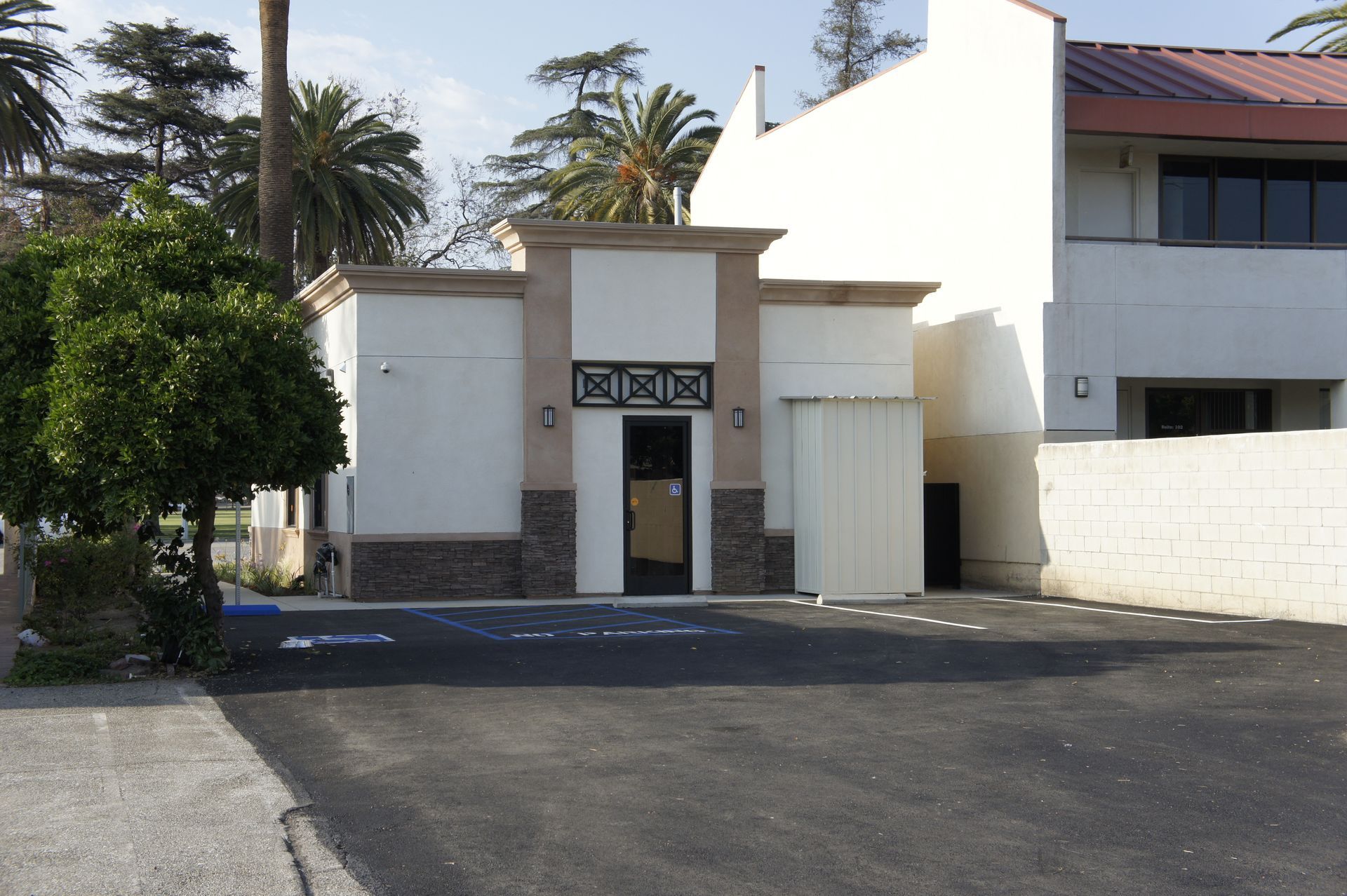 Building with tan and brown accents, set in a paved parking lot.