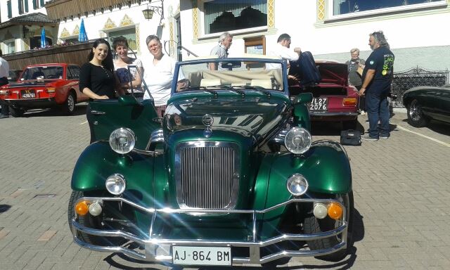 Un'auto d'epoca verde esposta all'aperto, con persone in piedi dietro di essa.