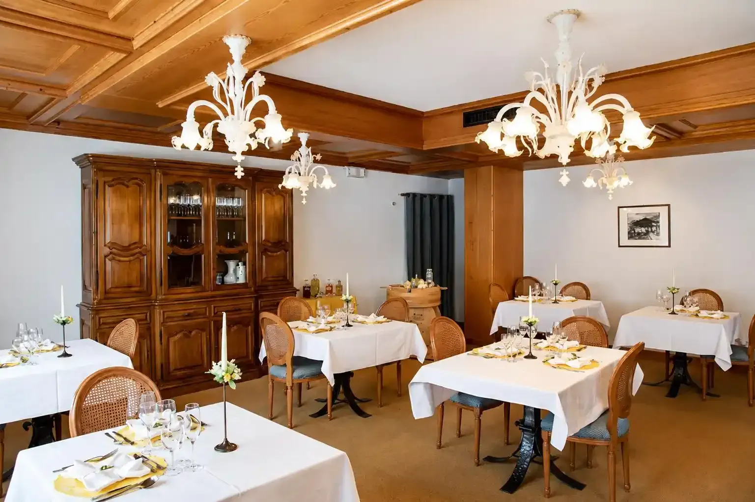 Elegante sala da pranzo d'albergo con tovaglie bianche, pannelli in legno e lampadari decorati.