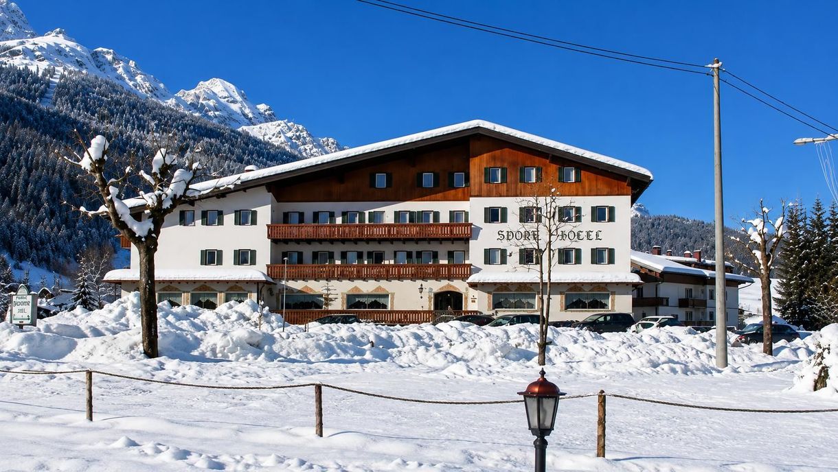 Rifugio alpino innevato con balconi in legno in un villaggio di montagna sotto un limpido cielo invernale