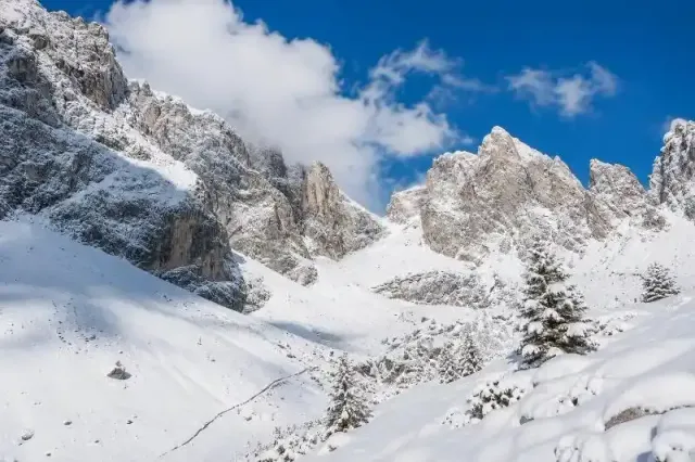 Cime montuose frastagliate e innevate sotto un cielo azzurro e limpido in un paesaggio invernale