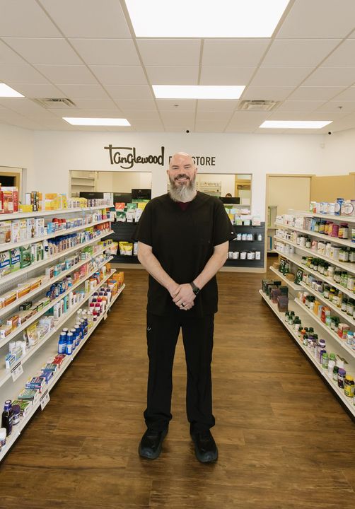 Man standing in the center aisle of a brightly lit grocery store, shelves stocked on both sides.