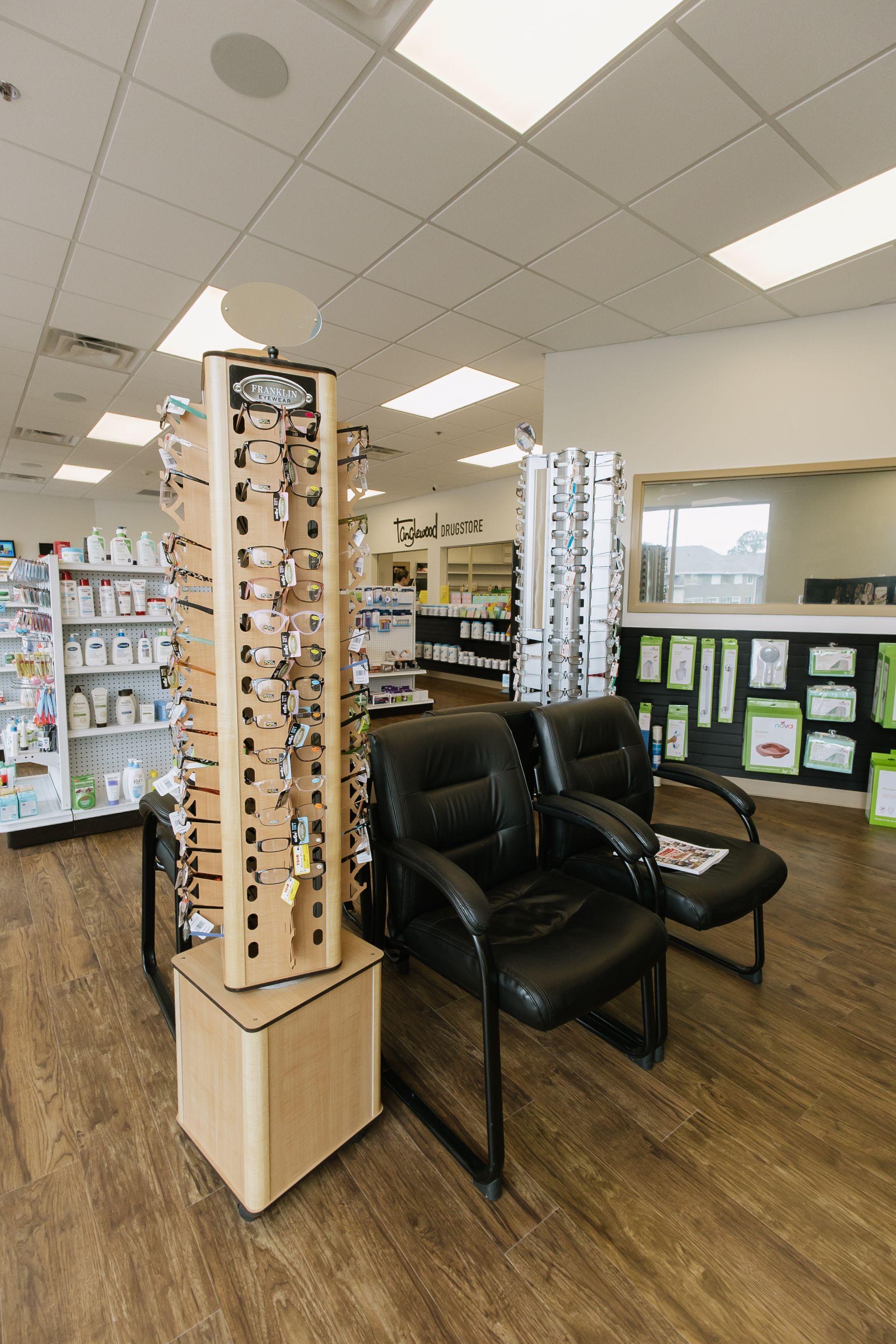 Eyewear display rack beside two black recliners in a bright optical shop waiting area