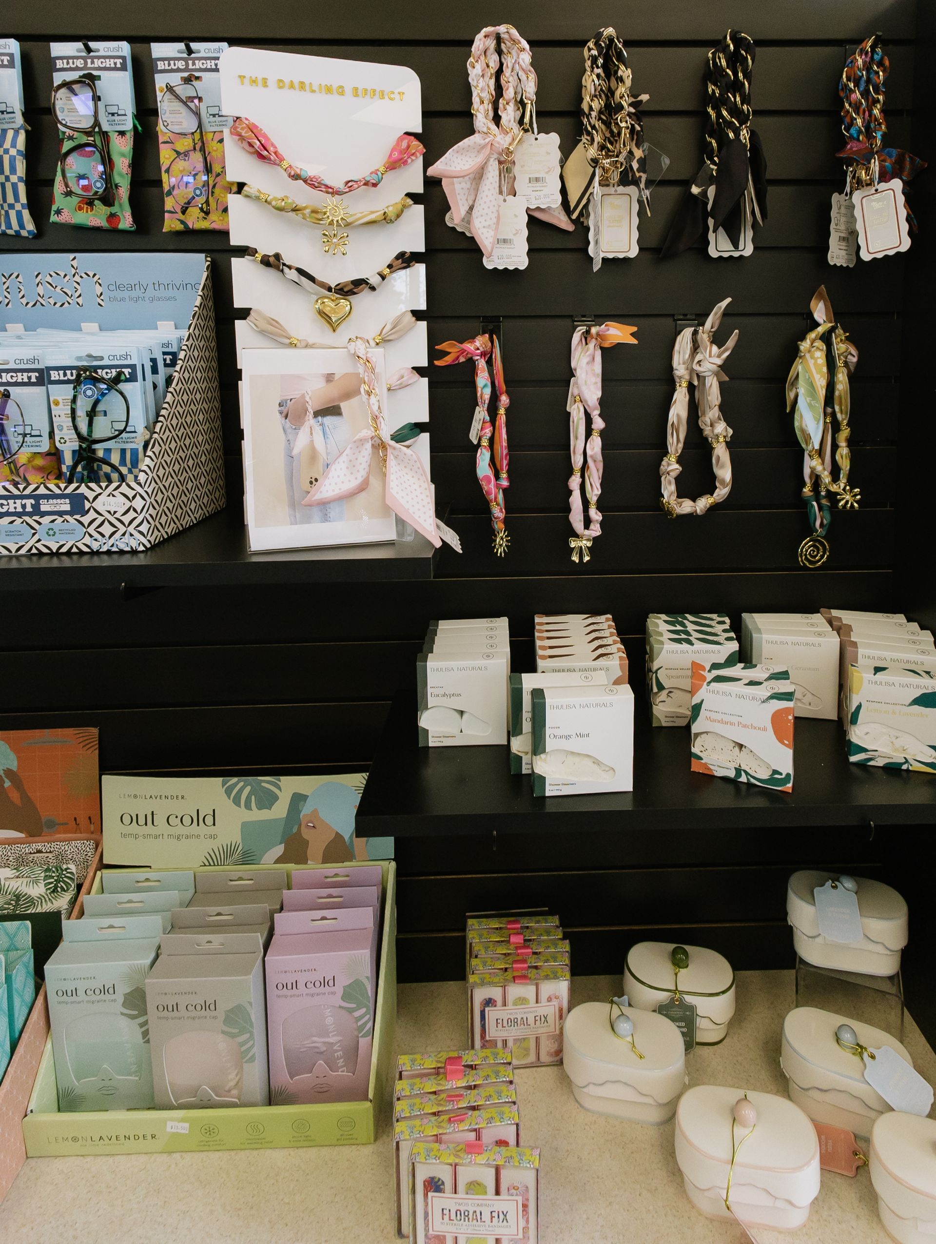 Assorted beaded bracelets and small accessories displayed on black retail shelves