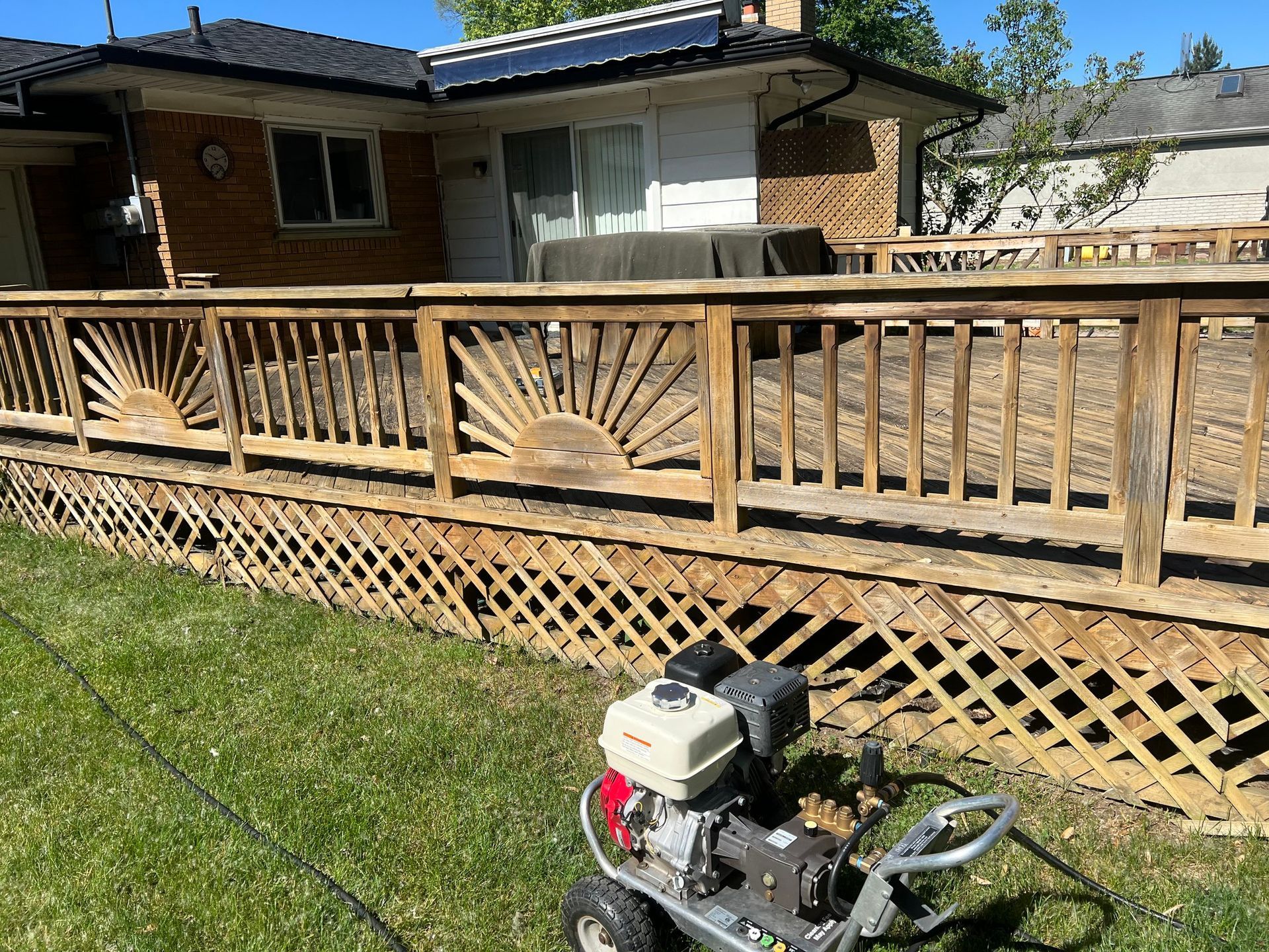 A pressure washer is sitting in front of a wooden deck.