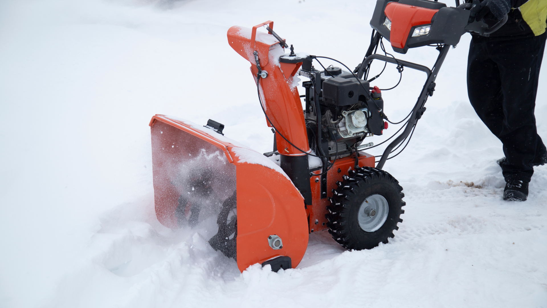 A person is pushing a snow blower through the snow.
