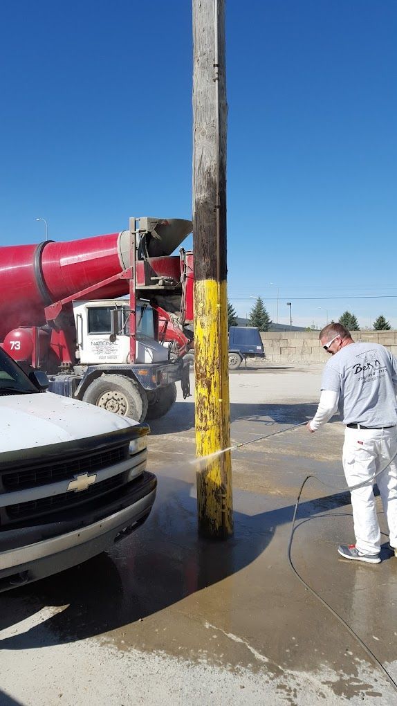 A man is washing a concrete pole next to a truck.