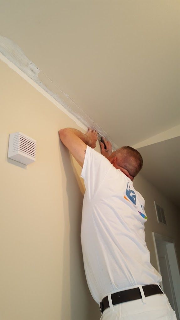 A man in a white shirt is working on a wall.