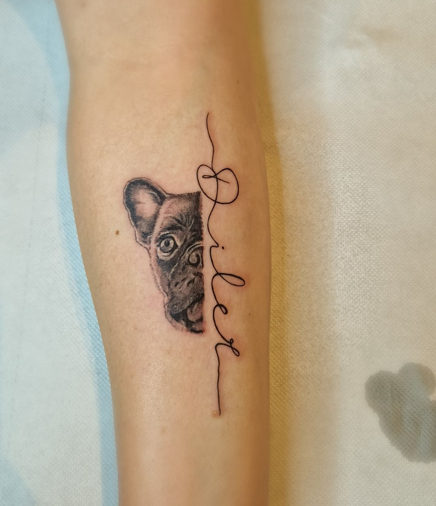 Tatuaggio di un cane nero con la scritta 
