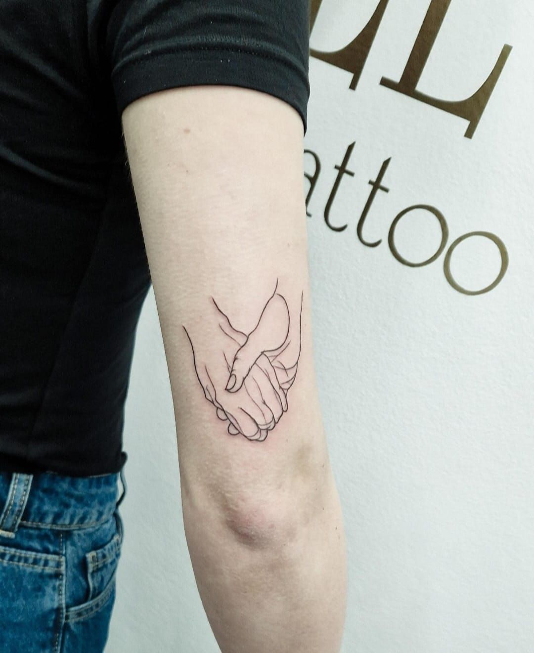 Profilo laterale di una persona con un tatuaggio floreale scuro sul viso e i capelli raccolti in uno chignon, che indossa un orecchino di perla.