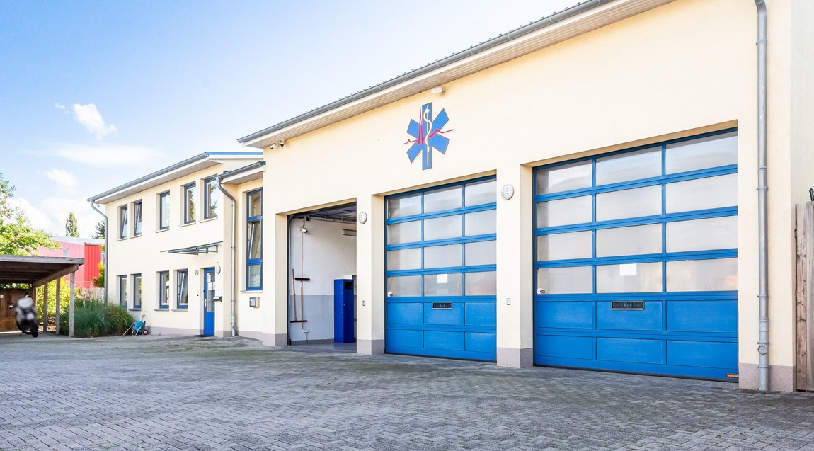 Außenansicht der Feuerwache mit blauen Garagentoren und einem Lebensstern-Symbol
