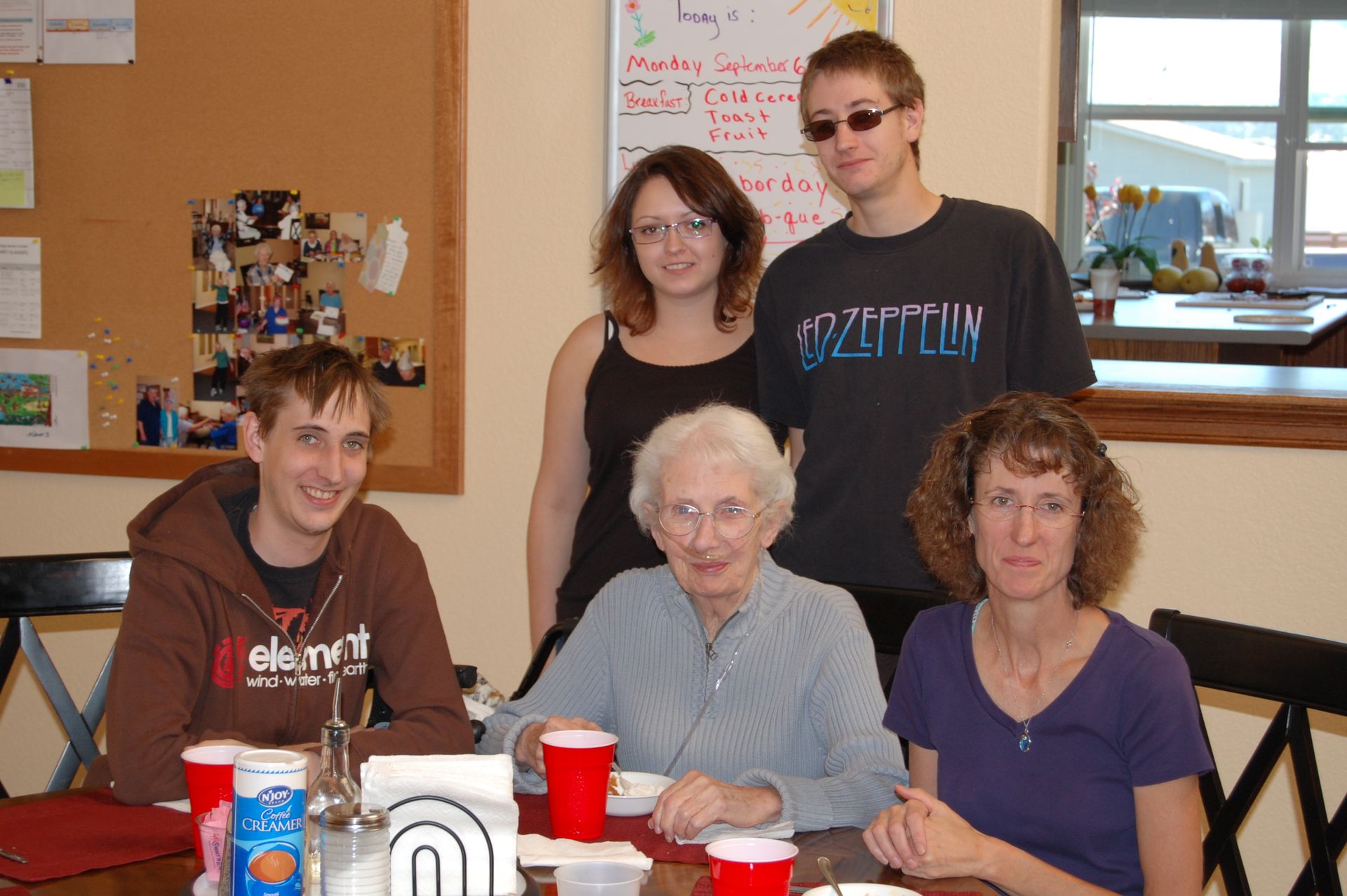 A group of people sitting around a table with one wearing a shirt that says led zeppelin