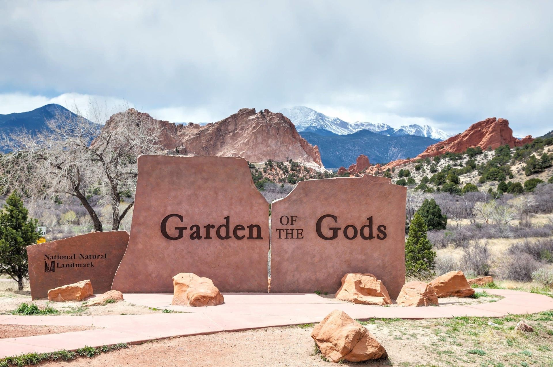 A garden of the gods sign with mountains in the background