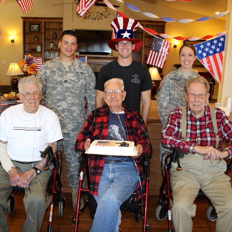 A man in a wheelchair holds a cake in front of a group of people