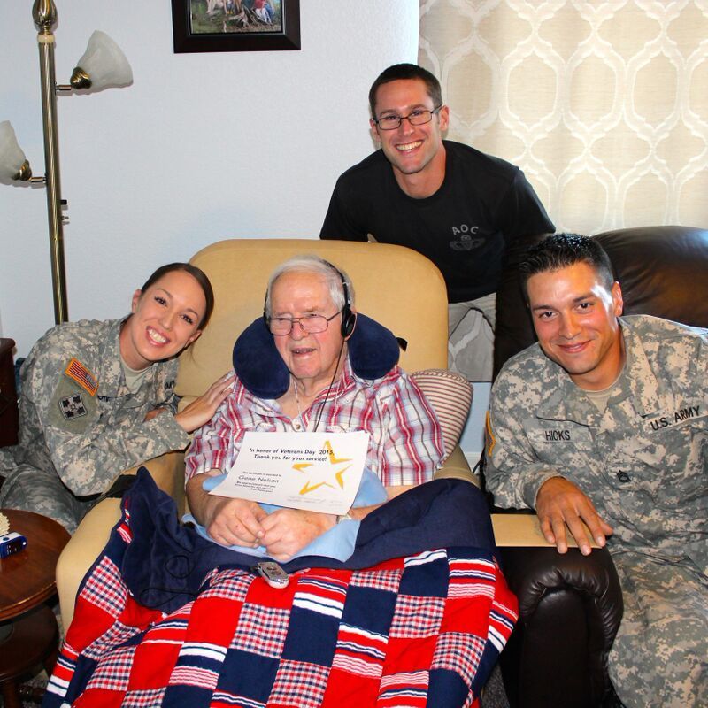 A group of soldiers are posing for a picture with an elderly man in a chair