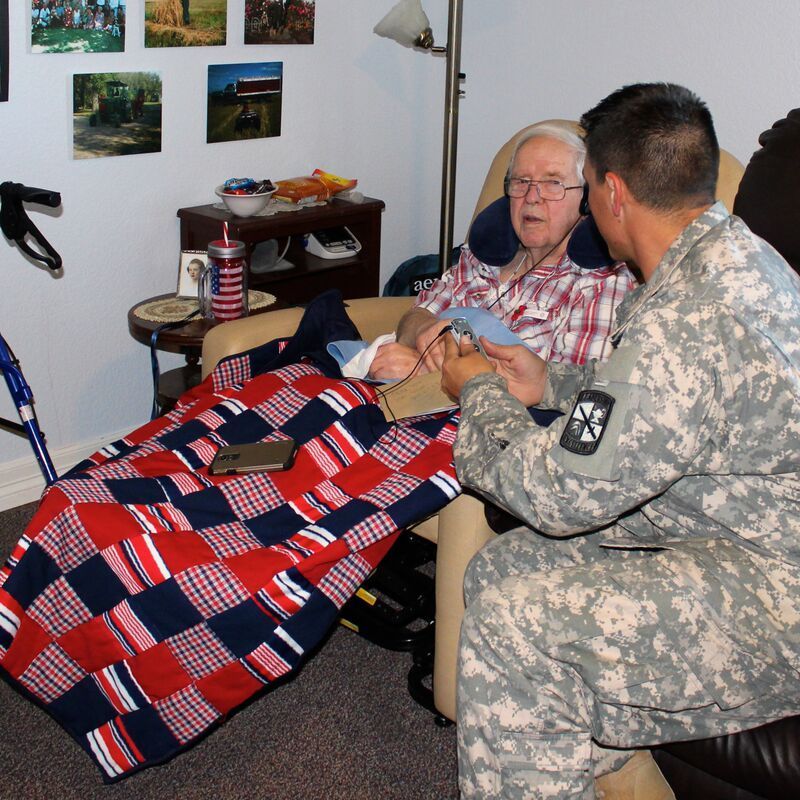 A man in a military uniform sits next to an older man in a chair