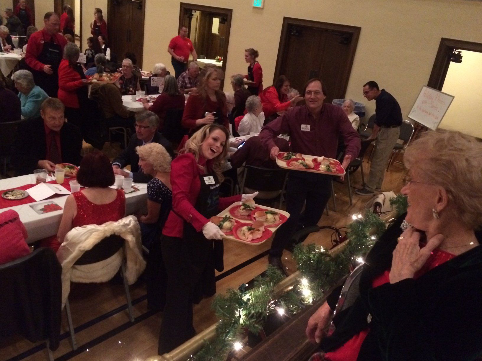A woman is carrying a tray of pizza in front of a crowd of people