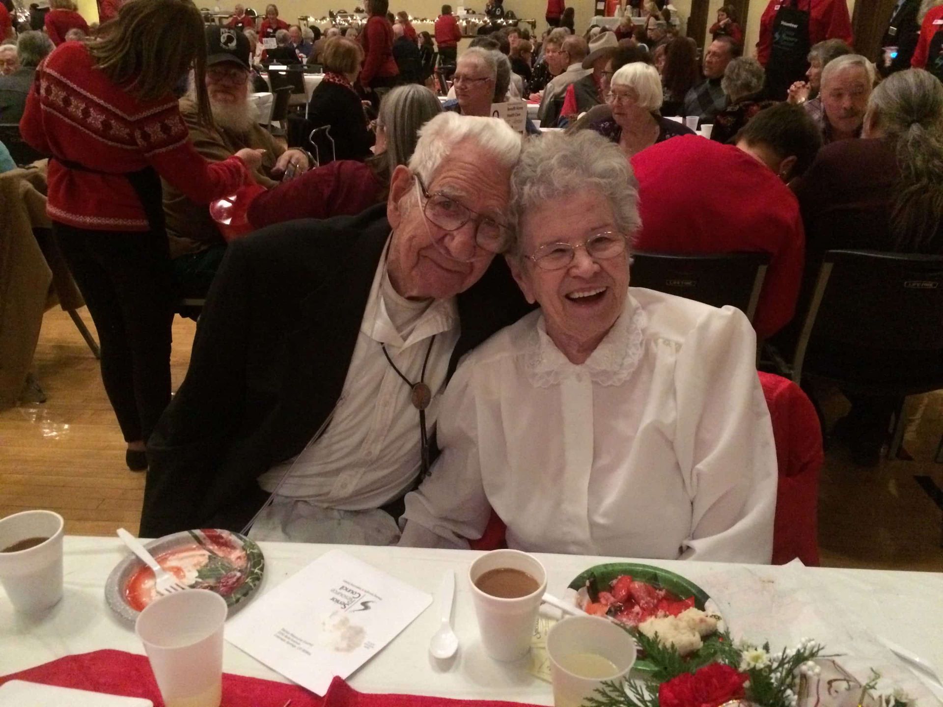 A man and woman are posing for a picture while sitting at a table.