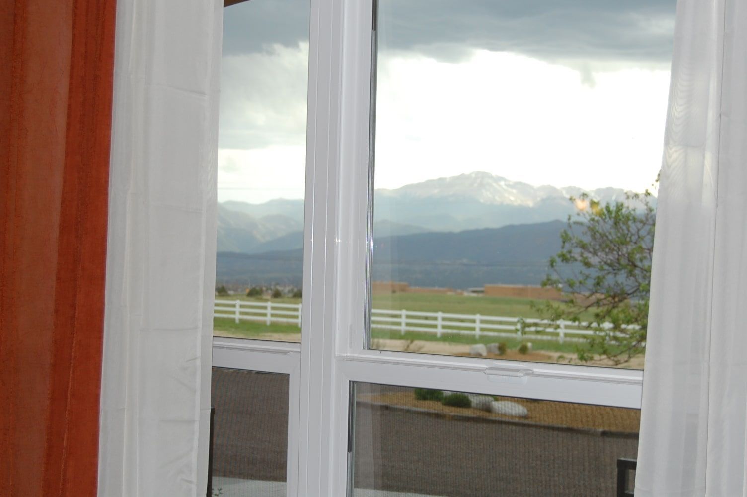 A window with a view of a field and mountains