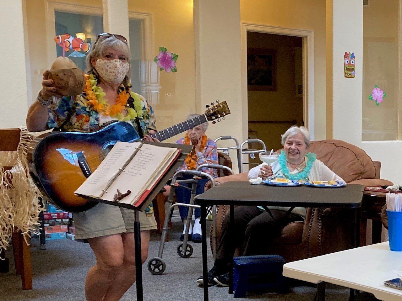 A woman is playing a guitar in front of a group of elderly people.
