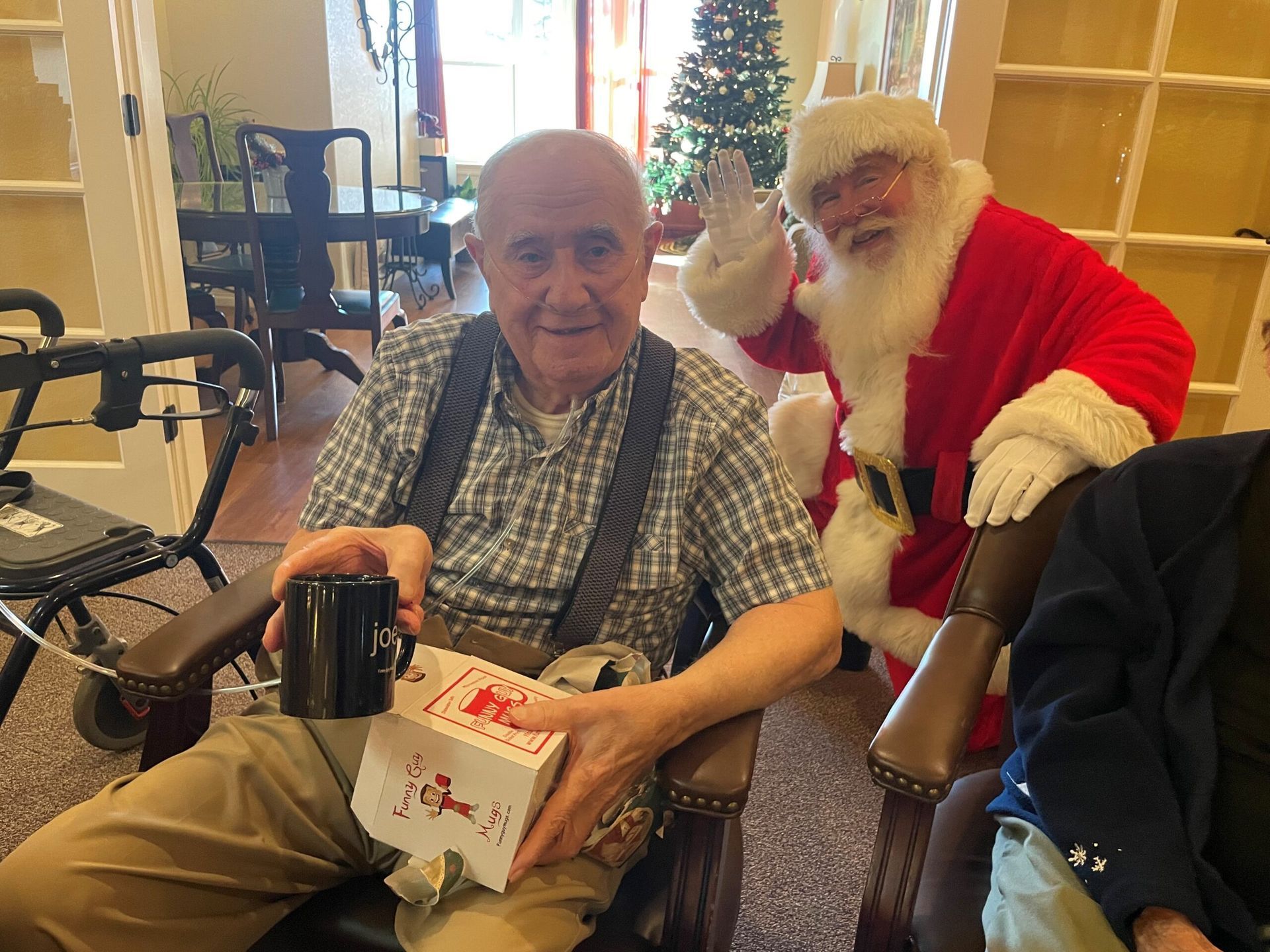 A man in a wheelchair is sitting next to a man dressed as santa claus.
