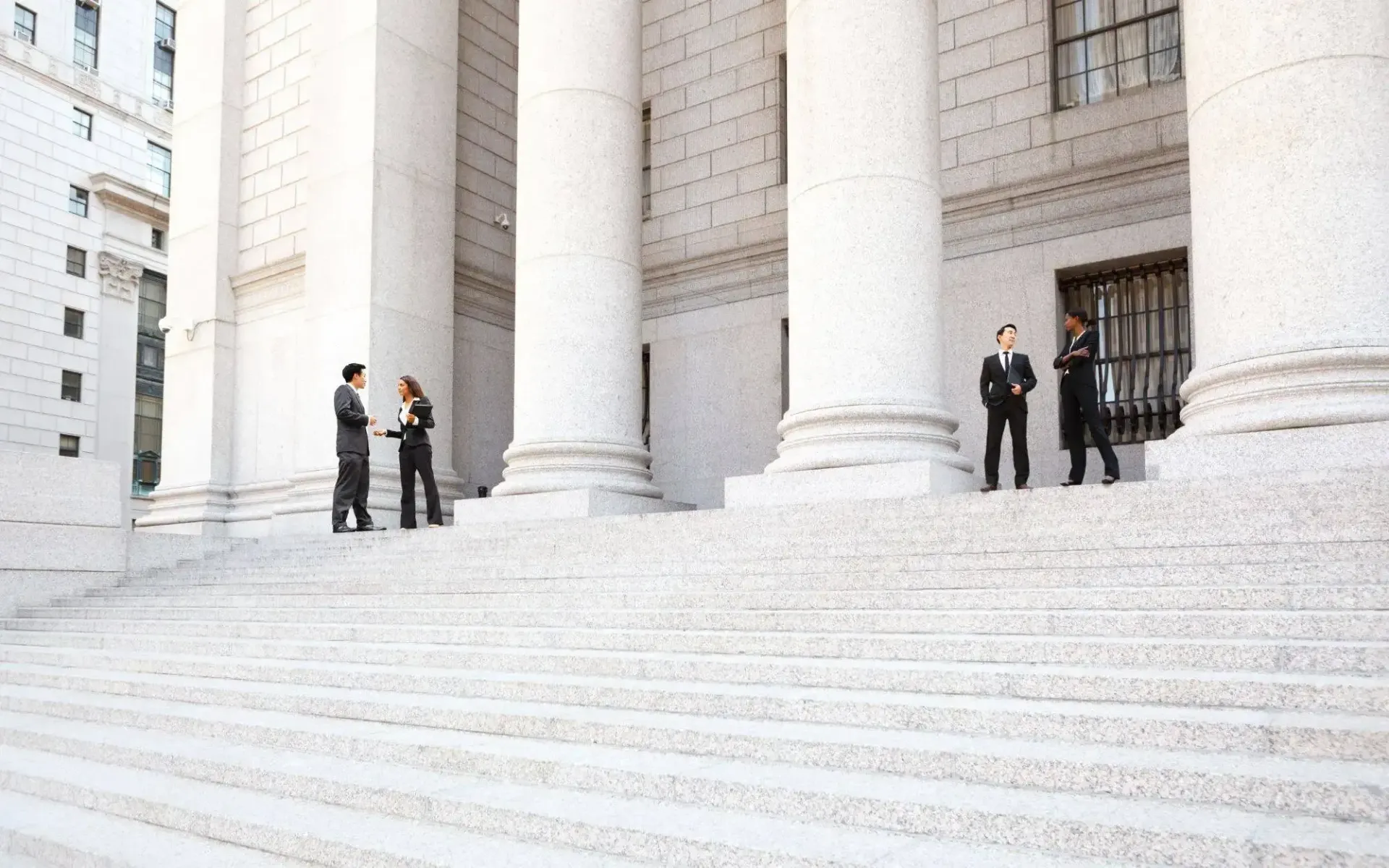 A group of people are standing on the steps of a building.