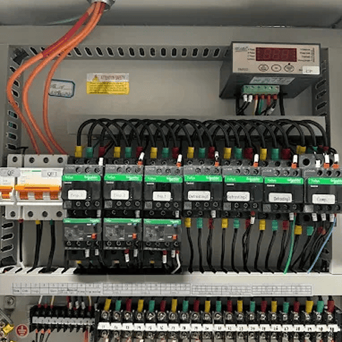 Electrical control panel with rows of relays, circuit breakers, and wiring inside a metal cabinet