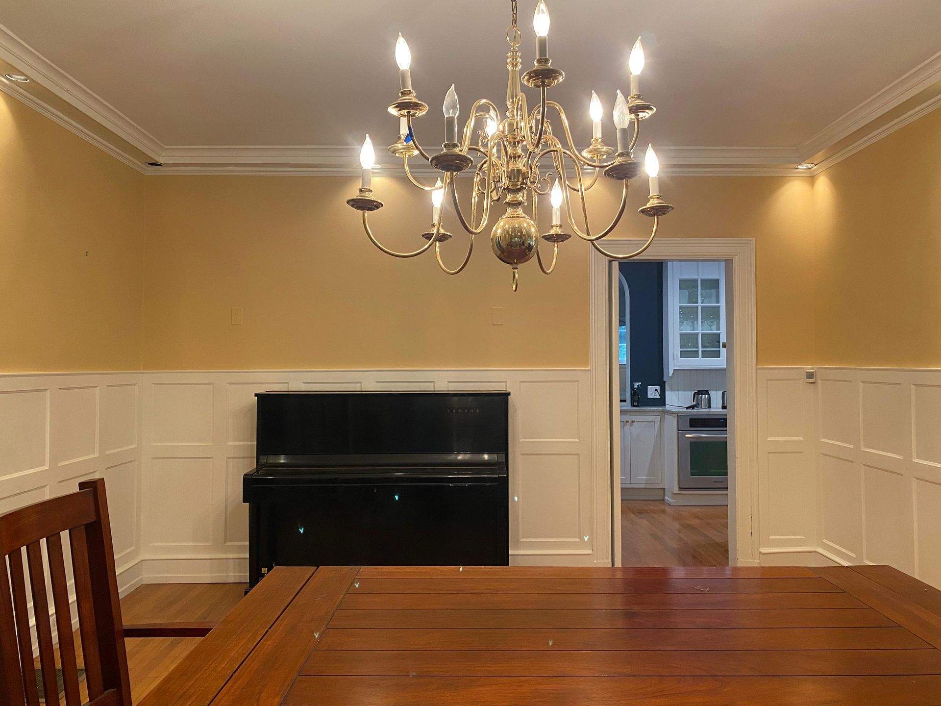 A dining room with a piano and a chandelier