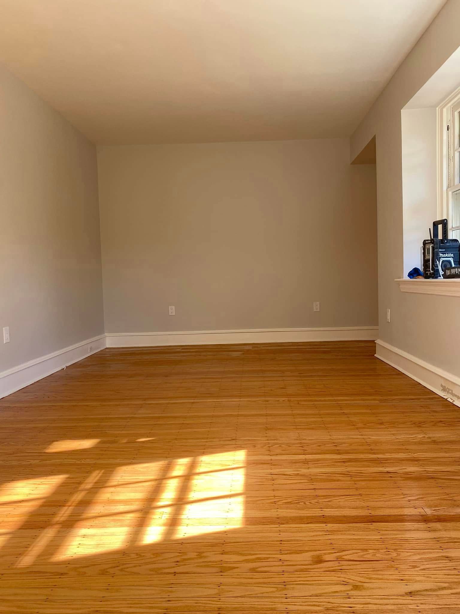 An empty living room with hardwood floors and a window.