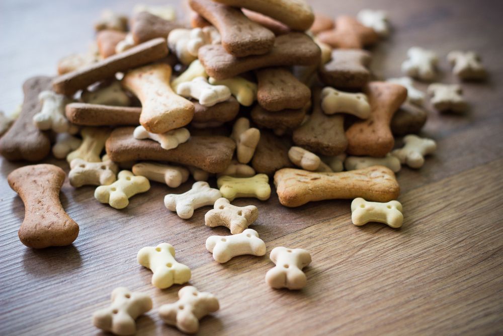 A Pile Of Dog Treats In The Shape Of Bones On A Wooden Table — Barking Happy Treats In Collombatti, NSW