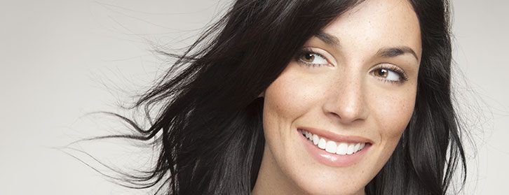 Close-up of a smiling woman with dark hair against a light background