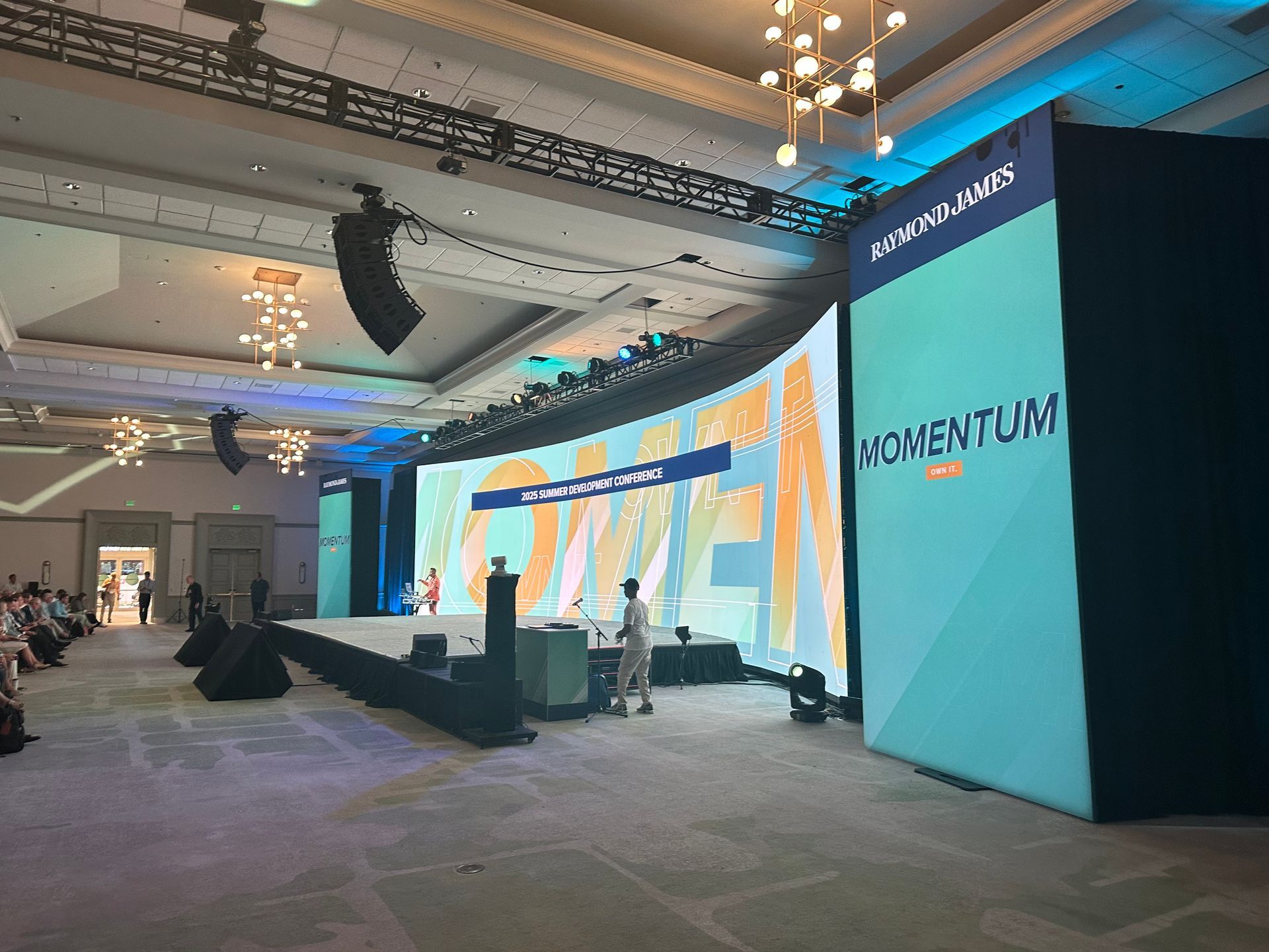 A spacious, carpeted conference room featuring a large, curved digital display showing the word