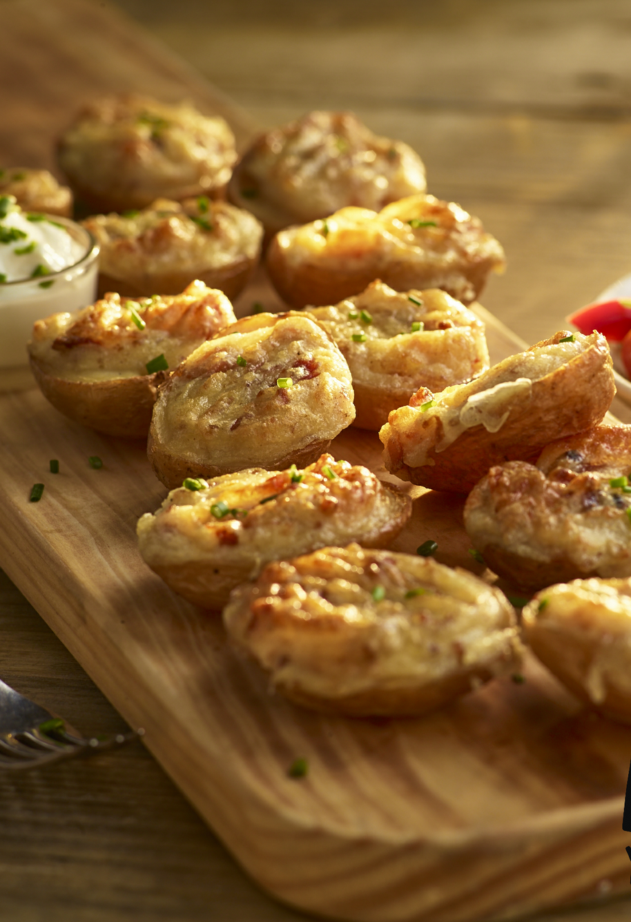 Tray of golden baked appetizers with herb garnish beside a green salad on a wooden table