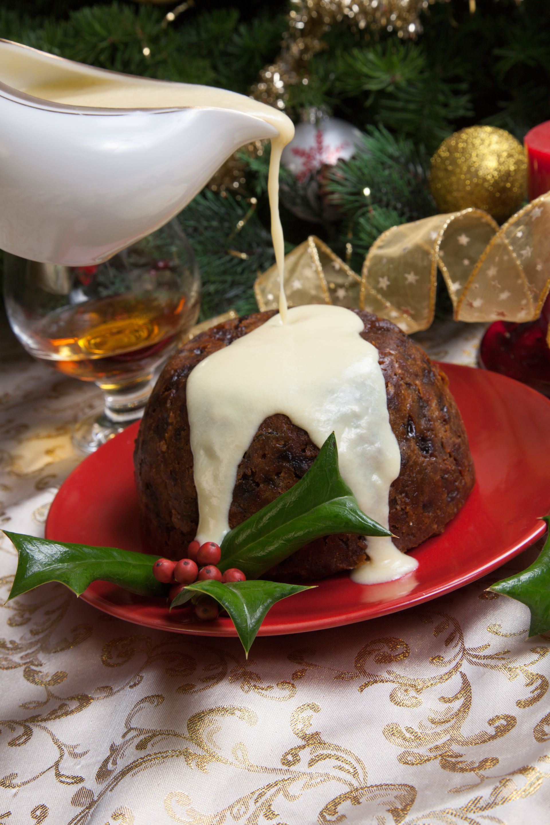Holiday dessert with cream sauce being poured over a bundt cake on a red plate, with festive decor