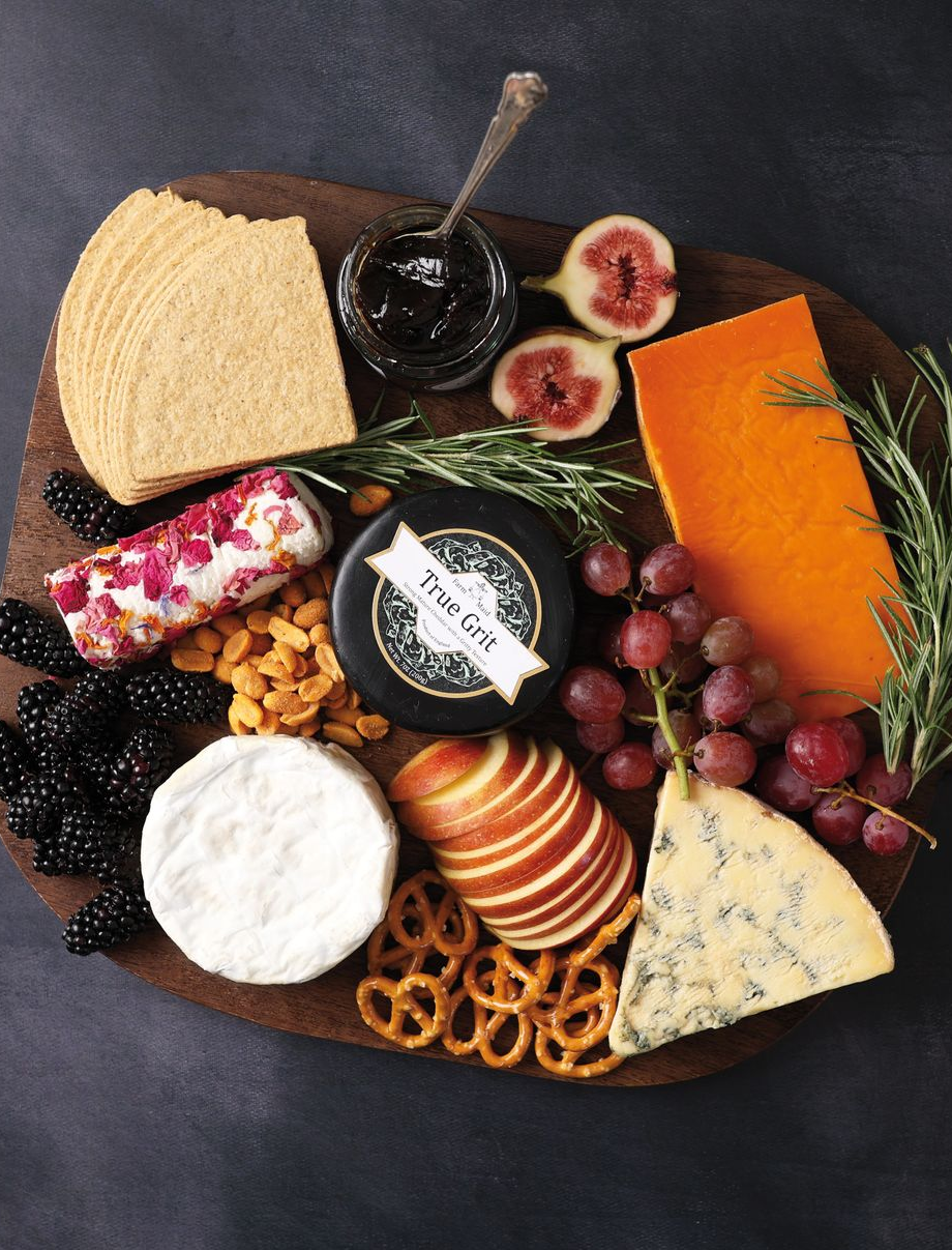Assorted cheeses, fruit, and crackers arranged on a rustic charcuterie board