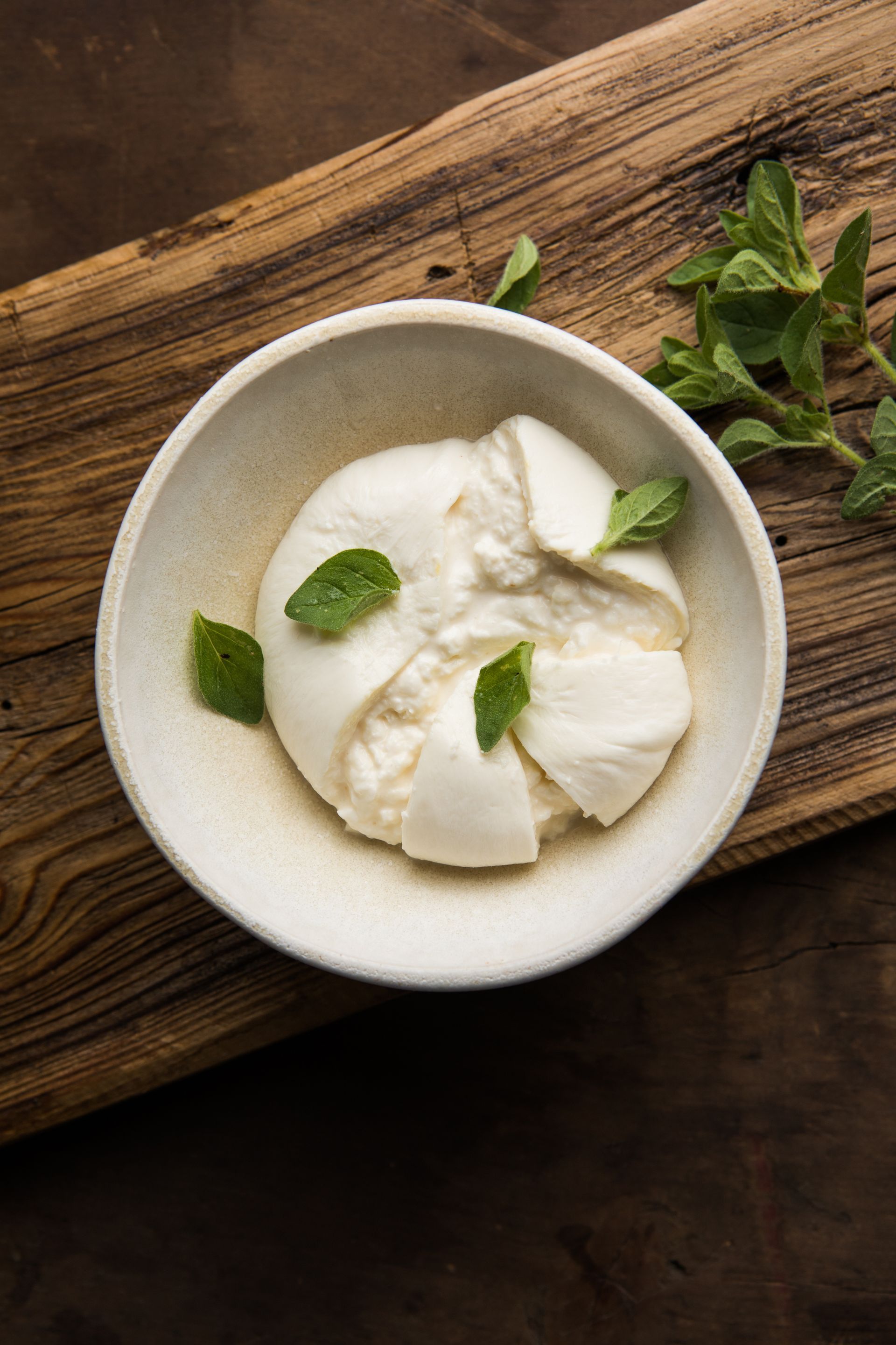 White cheese rounds in a bowl with mint leaves on a wooden table