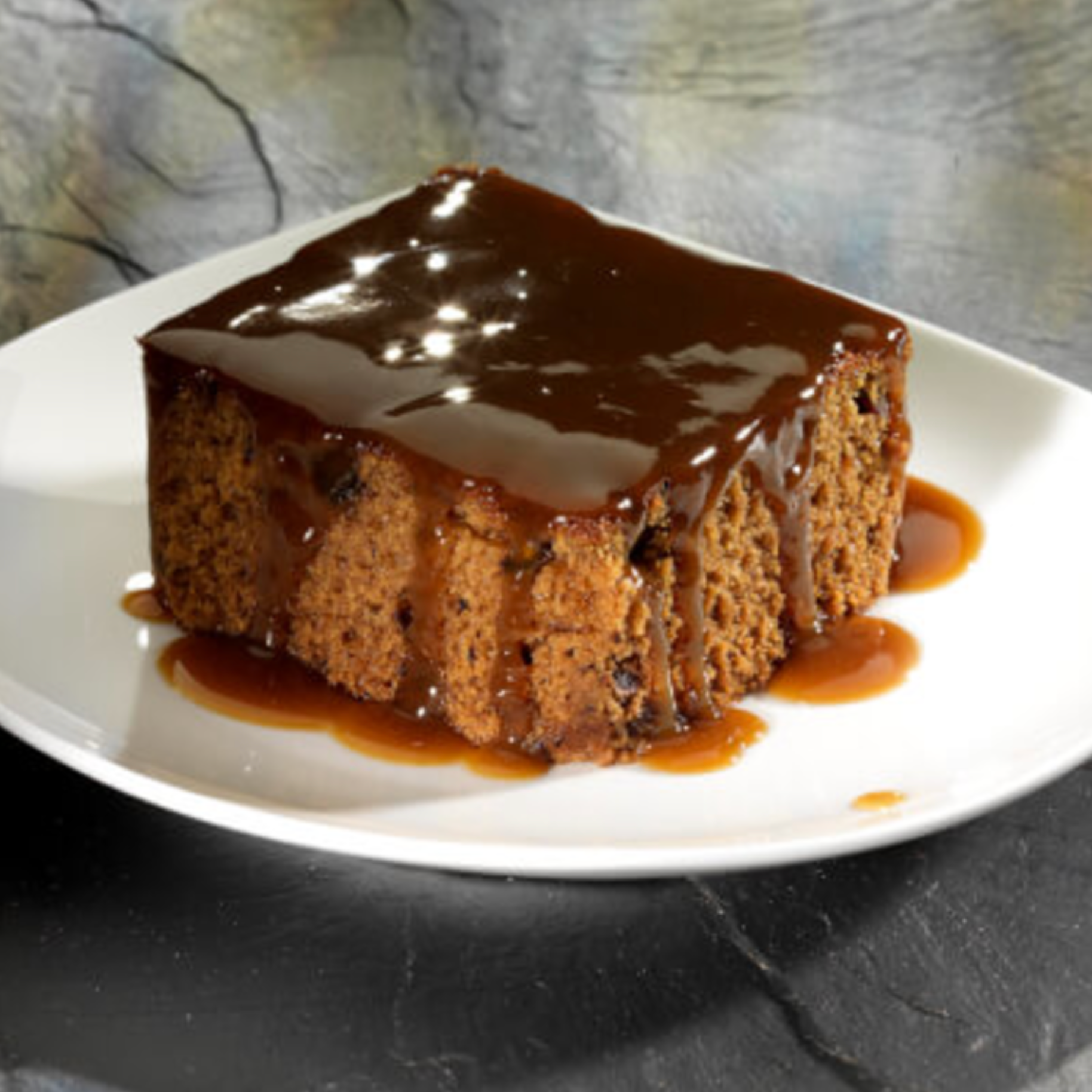Chocolate cake with glossy caramel glaze on a white plate