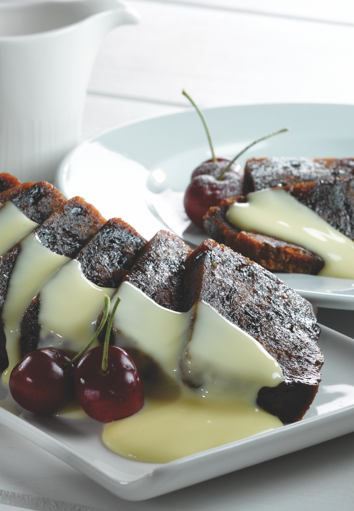 Slices of chocolate cake with vanilla sauce and cherries on a white plate