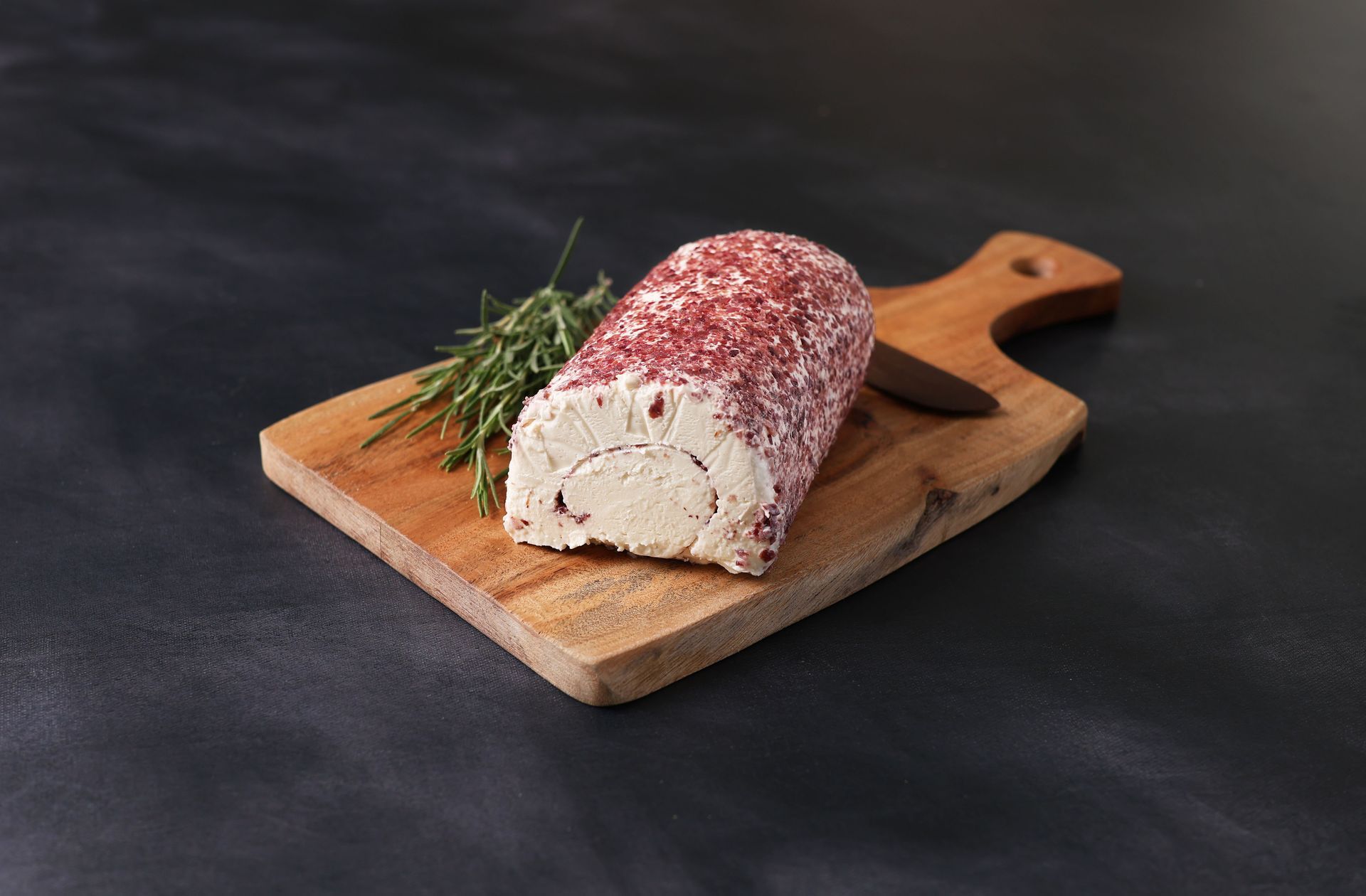 Sliced loaf topped with red seasoning on a wooden cutting board, garnished with herbs