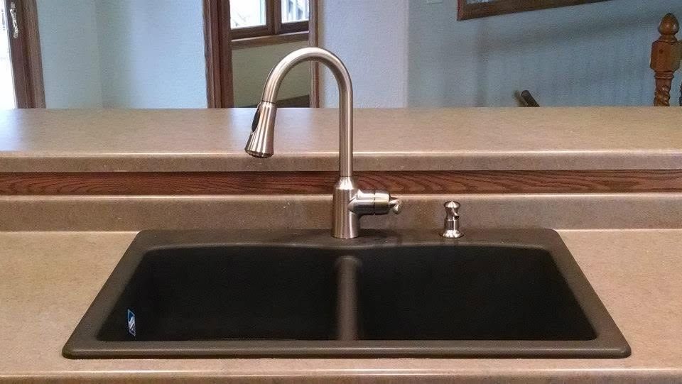 Kitchen sink with black basin, chrome faucet, and wooden countertop near a pass-through window