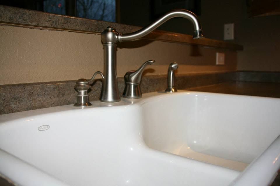 White kitchen sink with chrome faucet and counter, viewed close-up from above