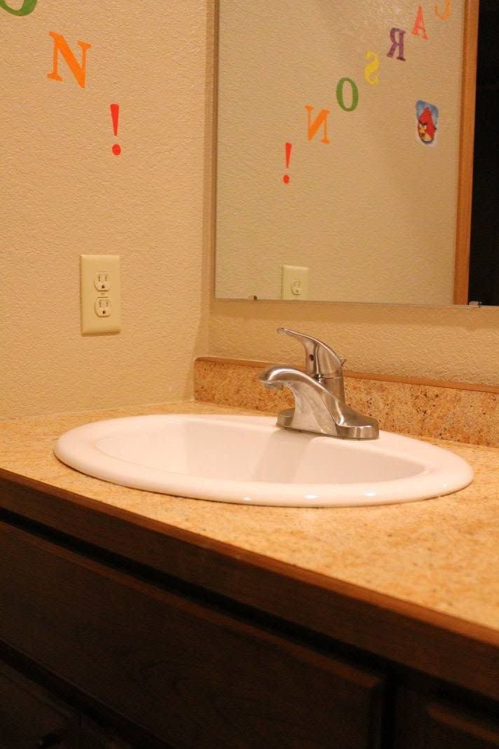Bathroom sink and mirror with colorful letter stickers on the wall and mirror.