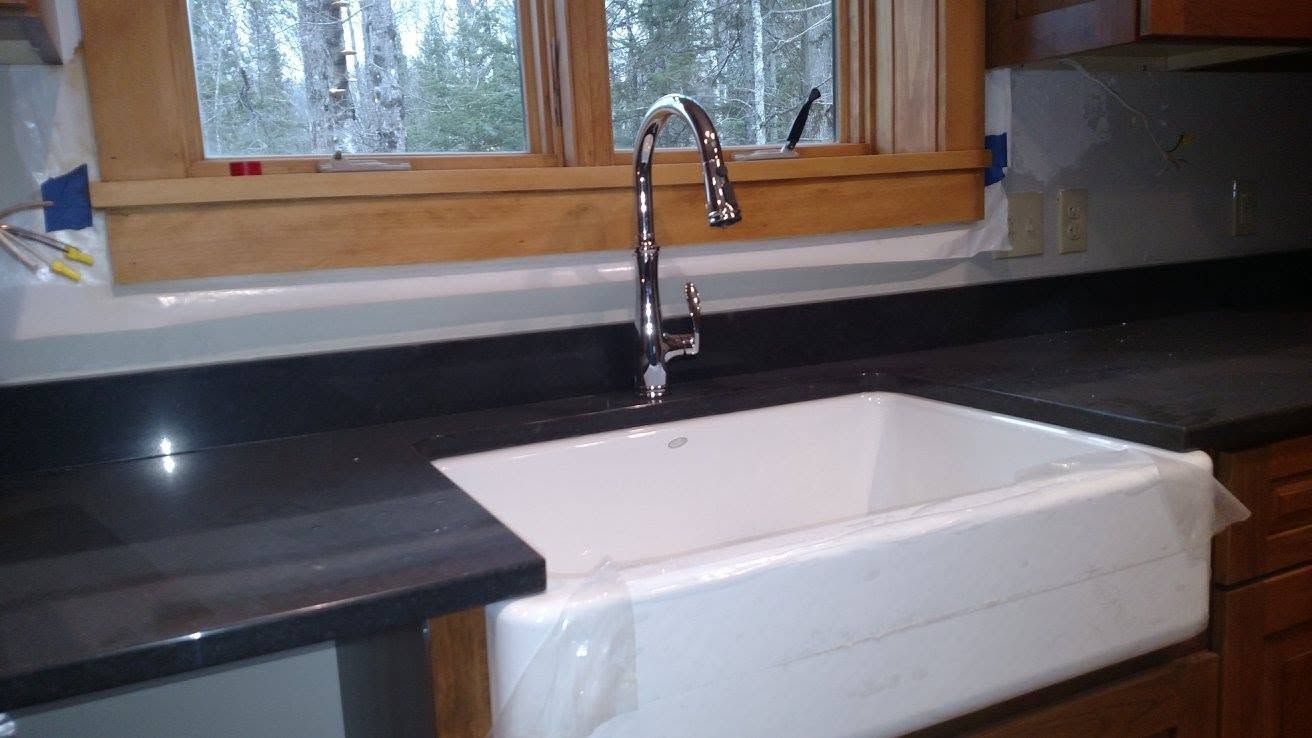 Kitchen sink under window with black countertops and a chrome faucet