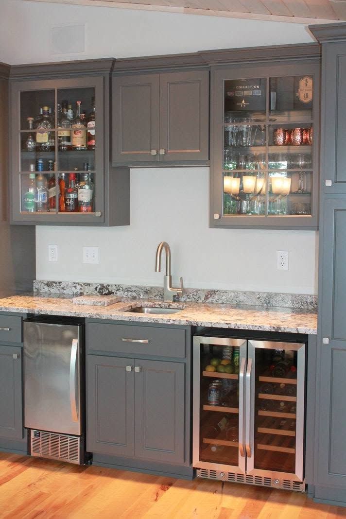 Gray kitchen wet bar with glass-front cabinets, sink, dishwasher, and wine fridge against a marble countertop