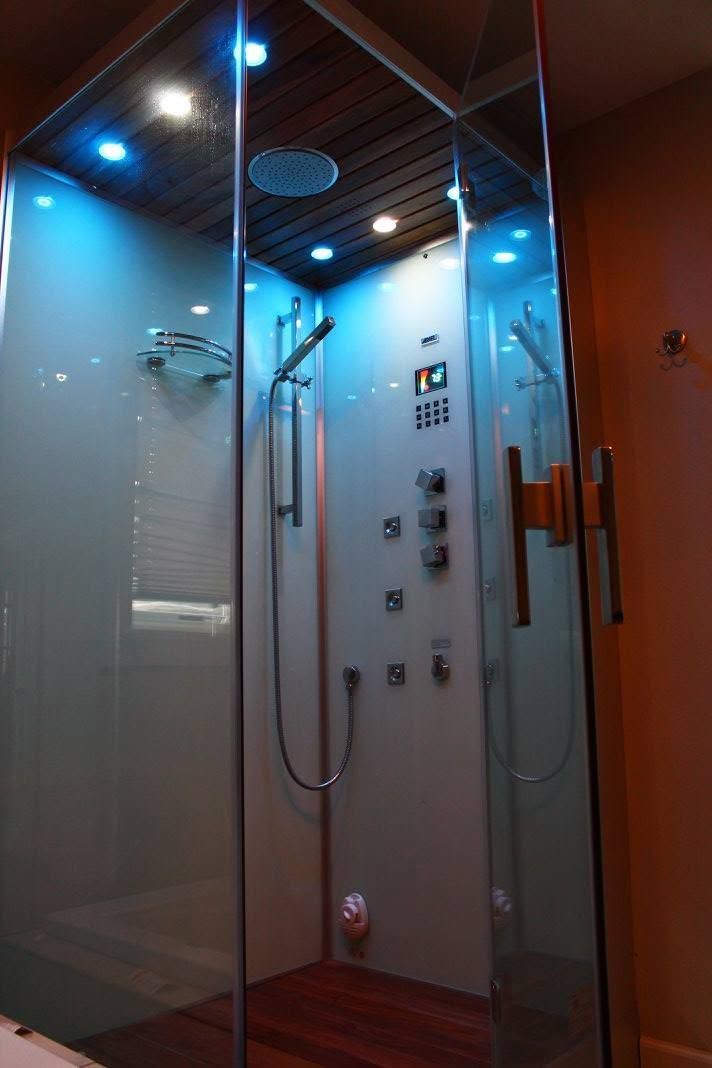 Glass shower stall with chrome fixtures and blue-lit ceiling panels